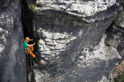 Ein junger Mann klettert durch einen Felskamin an den Papststeinen, Sächsische Schweiz, Elbsandsteingebirge, Sachsen, Deutschland, MR
