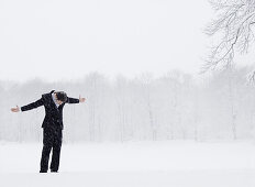 Young man standing in snow flurry, Munich, Bavaria, Germany