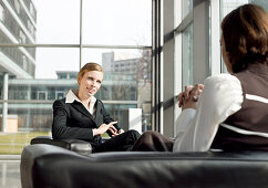 Businesswomen sitting in armchairs discussing, Munich, Bavaria, Germany