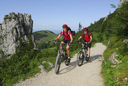 Couple mountainbiking, Kampenwand, Chiemgau range, Chiemgau, Bavaria, Germany