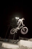 Ein Teenager beim Sprung mit seinem BMX Rad bei Nacht, Wagram, Österreich