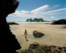 Woman walking through tidal pools at lowtide at Wharariki Beach, northwest coast, South Island, New Zealand