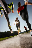 Four people running along road, Strasslach-Dingharting, Bavaria, Germany