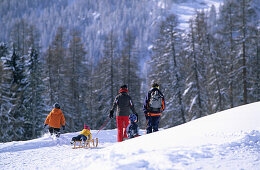 Family walking through winter scenery, ski resort of Motta Naluns, Scuol, Lower Engadine, Engadine, Grisons, Switzerland