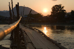 Holzbrücke über dem Fluss Nam Xong bei Sonnenuntergang, Vang Vieng, Provinz Vientiane, Laos