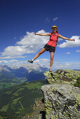 Frau balanciert auf einem Felsen, Berchtesgadener Alpen im Hintergrund, Salzburg, Österreich