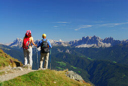 couple on trail with view to Dolomites with Peitlerkofel and Geislergruppe range, hut Radlseehuette, Sarntaler Alpen, Sarntal range, South Tyrol, Italy