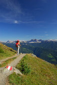 young woman on trail with view to Dolomites with Peitlerkofel, Geislergruppe and Sella range, hut Radlseehuette, Sarntaler Alpen, Sarntal range, South Tyrol, Italy
