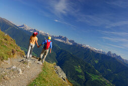 couple running on trail with view to Dolomites with Peitlerkofel, Geislergruppe, Sella and Langkofelgruppe range, hut Radlseehuette, Sarntaler Alpen, Sarntal range, South Tyrol, Italy