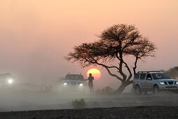 A person and three all-terrain vehicles in front of the setting sun, Al Hajar mountains, Oman, Asia, Oman, Asia