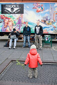 Small child standing in front of teenagers, youths, playground, Ingolstadt, Bavaria, Germany