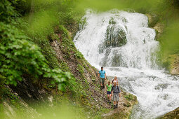 Hikers near a waterfall, Werdenfelser Land, Bavaria, Germany