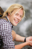 Young man drinking from waterfall, Werdenfelser Land, Bavaria, Germany