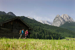 Hikers near wooden lodge, Werdenfelser Land, Bavaria, Germany