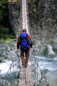 Man on a suspension bridge above the Rees Dart River, Mount Aspiring National Park, South Island, New Zealand, Oceania