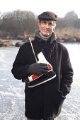 Senior man with ice skates at lake Ammersee, Upper Bavaria, Germany