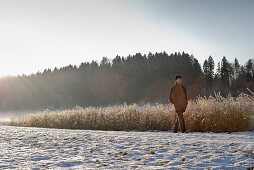 Senior man walking through winter scenery, Windach, Upper Bavaria, Germany