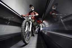 Mountain biker standing on an escalator, Ischgl, Tyrol, Austria