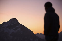 Young man in sunset, mountains in background, Oberstdorf, Bavaria, Germany