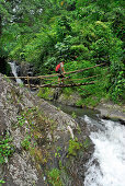 A man on a bridge above a waterfall, North Bali, Indonesia, Asia