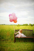 Girl, age 3 looking at balloons.