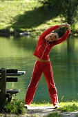 Young woman doing stretching exercises near a lake, Training, Jogging, Fitness, South Tyrol, Italy