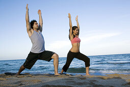 Young couple doing voga on the beach