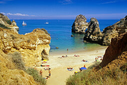 Blick auf Menschen am Strand an der Felsküste, Praia do Camilo, Algarve, Portugal, Europa