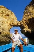 Älterer Mann am Steuer eines Bootes unter blauem Himmel, Ponta da Piedade, Algarve, Portugal, Europa