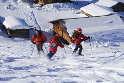 Woman downhill skiing towards group of backcountry skiers, Kitzbuehel Alps, Tyrol, Austria