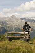 Hiker (MR) in the hiking area of Klausberg, view towards Zillertaler Alps, Tauferer Ahrntal, South Tyrol, Italy
