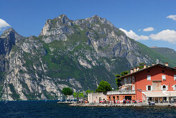 Blick über den Gardasee auf ein Straßencafe an der Promenade, Nago-Torbole, Trentino-Südtirol, Italien