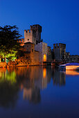 Reflection of illuminated Castello Scaligero in lake Garda, Sirmione, Lombardy, Italy