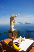 Young woman lying reading at a terrace with sea view, Capri, Italy, Europe
