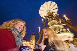 Two women drinking glogg, Christmas pyramid in background, Christmas market, Freiberg, Ore mountains, Saxony, Germany