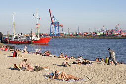 Sunbathing at sandy beach of river Elbe, light ship Elbe 3 in background, Oevelgoenne, Hamburg, Germany