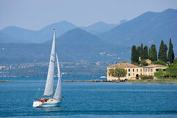 Segelboot steuert Punta San Vigilio bei Garda an. Das Haus an der Lanspitze ist das älteste Hotel am Gardasee, Provinz Verona, Veneto, Italien