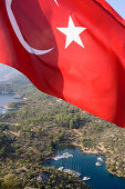 Die türkische Flagge und Blick auf die kleine Bucht Kapi Creek, Fethiye Bucht, Türkei, Europa