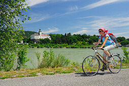 Radfahrerin fährt entlang der Donau, Schloss Persenbeug im Hintergrund, Donauradweg Passau Wien, Persenbeug, Niederösterreich, Österreich