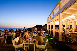 Tourists dining in a fish Restaurant on the beach at sunset, Praia do Evaristo, Albufeira, Algarve, Portugal