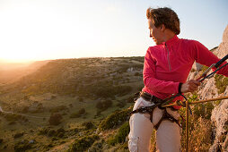 Frau mittleren Alters klettert und betrachtet den Sonnenuntergang, Provinz Sassari, Sardinien, Italien, Europa