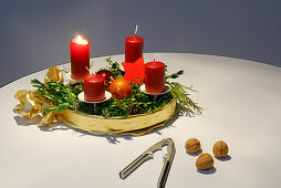 Advent wreath with burning candle, with nutcracker and walnuts in foreground