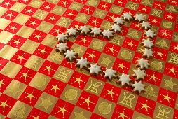 Weihnachtsgebäck Zimtsterne liegen in Herzform auf Geschenkpapier
