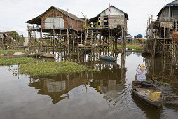Woman in a boat in front of fishing village Kampong Phlug at Tonle Sap Lake, Siem Reap Province, Cambodia, Asia
