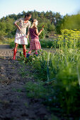 Mother and daughter (8-9 years) in vegetable garden, Lower Saxony, Germany