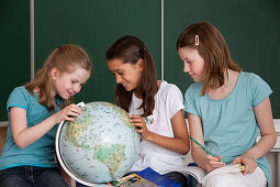 Schoolgirls with globe in classroom, Hamburg, Germany