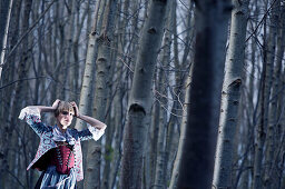 Young woman wearing a dirndl, traditional costume, standing in a forest, Kaufbeuren, Bavaria, Germany
