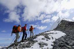 Three mountain hikers ascending over ridge towards Hochfeiler, Zillertal Alps, South Tyrol, Italy