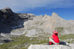Frau sitzt auf Felsen und schaut auf Lavarella, Naturpark Fanes-Senes-Prags, Dolomiten, Trentino-Südtirol, Italien