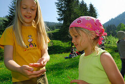 Zwei Mädchen betrachten etwas in der Hand, Bayerische Alpen, Oberbayern, Bayern, Deutschland